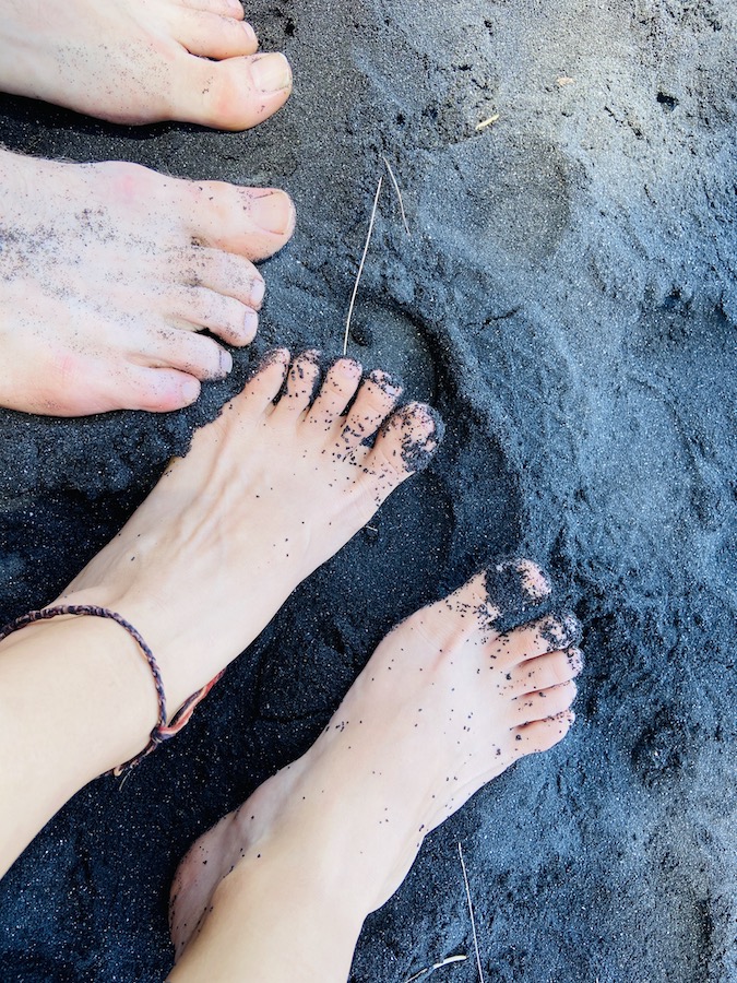 Black sand covering feet