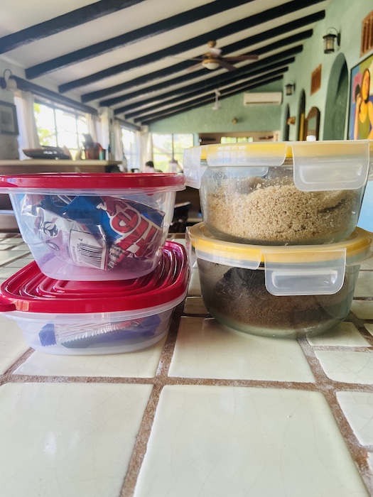Tupperware with open bags of snacks 